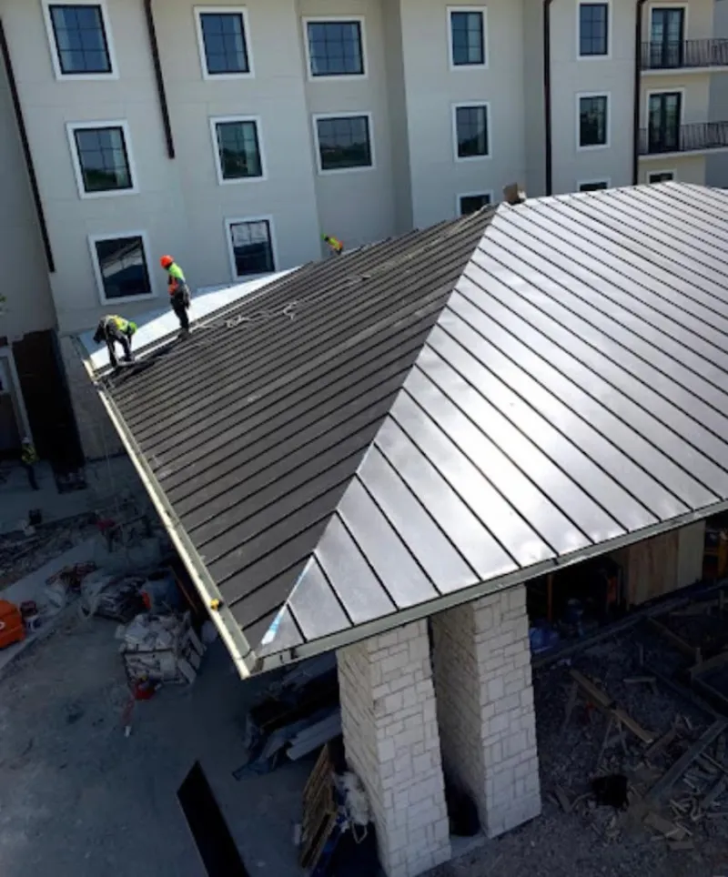 Crew installing standing seam metal roof panels on a commercial project in Firebaugh